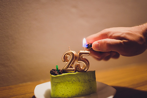Venticinque anni di anniversario. torta di compleanno al pistacchio con candele accese a forma di numero venticinque